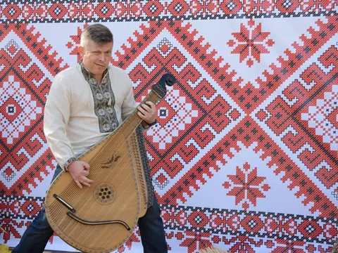 Віктор із бандурою на тлі вишивки